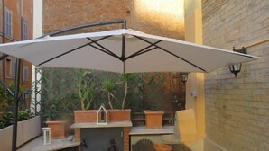 A patio area with a white umbrella, a small table, and potted plants. - Cozy Independent House with Large Terrace in Heart of Monti (Roma)