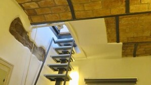 A staircase leading to a second floor with a brick ceiling and a light fixture. - Cozy Independent House with Large Terrace in Heart of Monti (Roma)