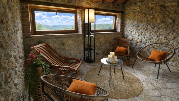 A stone-walled room with two windows, wicker chairs, a small table with candles, and a view of a forested landscape. - SCAPPO IN UMBRIA, Casale al Lago (Baschi)