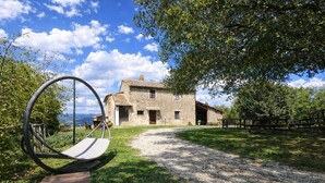 A stone building with a gravel path leading to it, surrounded by greenery. - SCAPPO IN UMBRIA, Casale al Lago (Baschi)