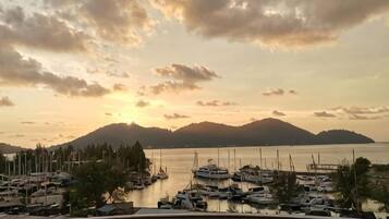 A marina with boats docked, a clear sky, and a distant mountain range.