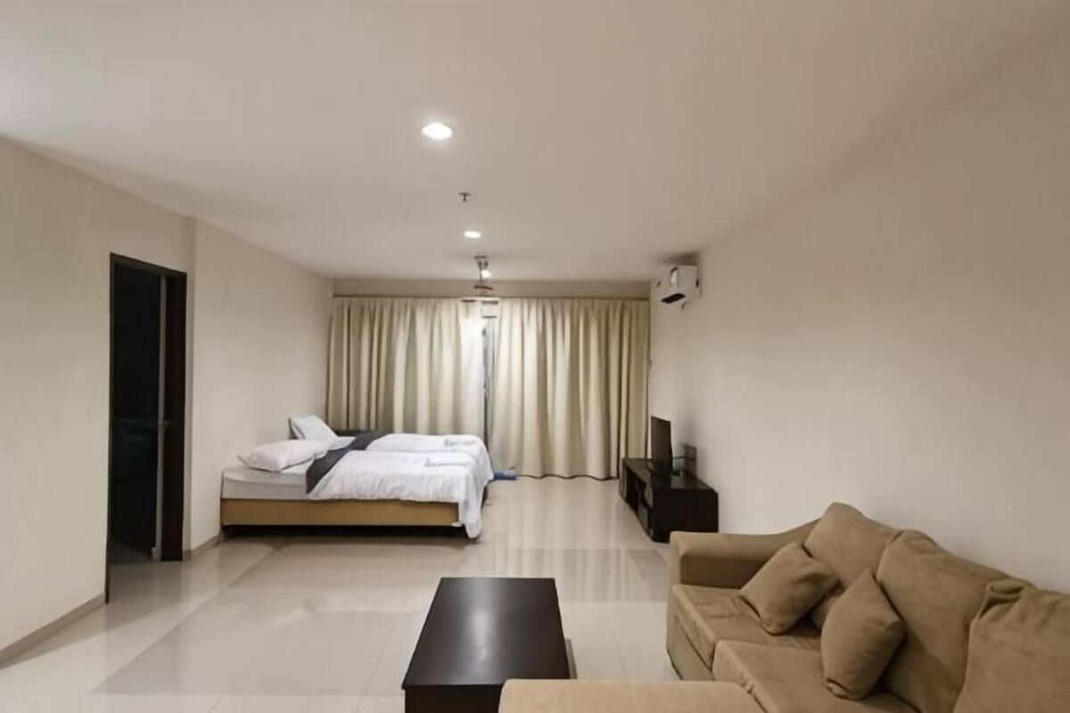A modern hotel room with a bed, a sofa, a coffee table, and a TV.