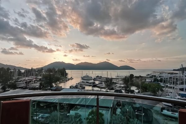 Un port de plaisance avec des bateaux, un ciel dĂ©gagĂ© et des montagnes Ă lâhorizon.