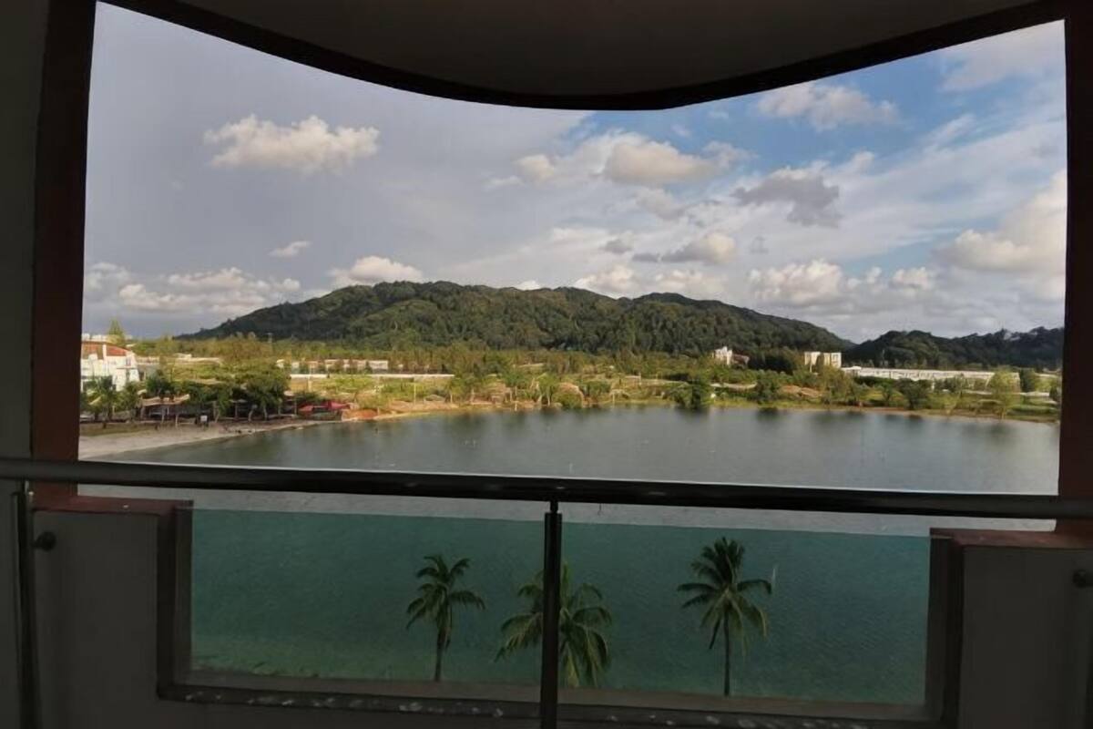 A view from a balcony with a lake, trees, and a mountain in the background.