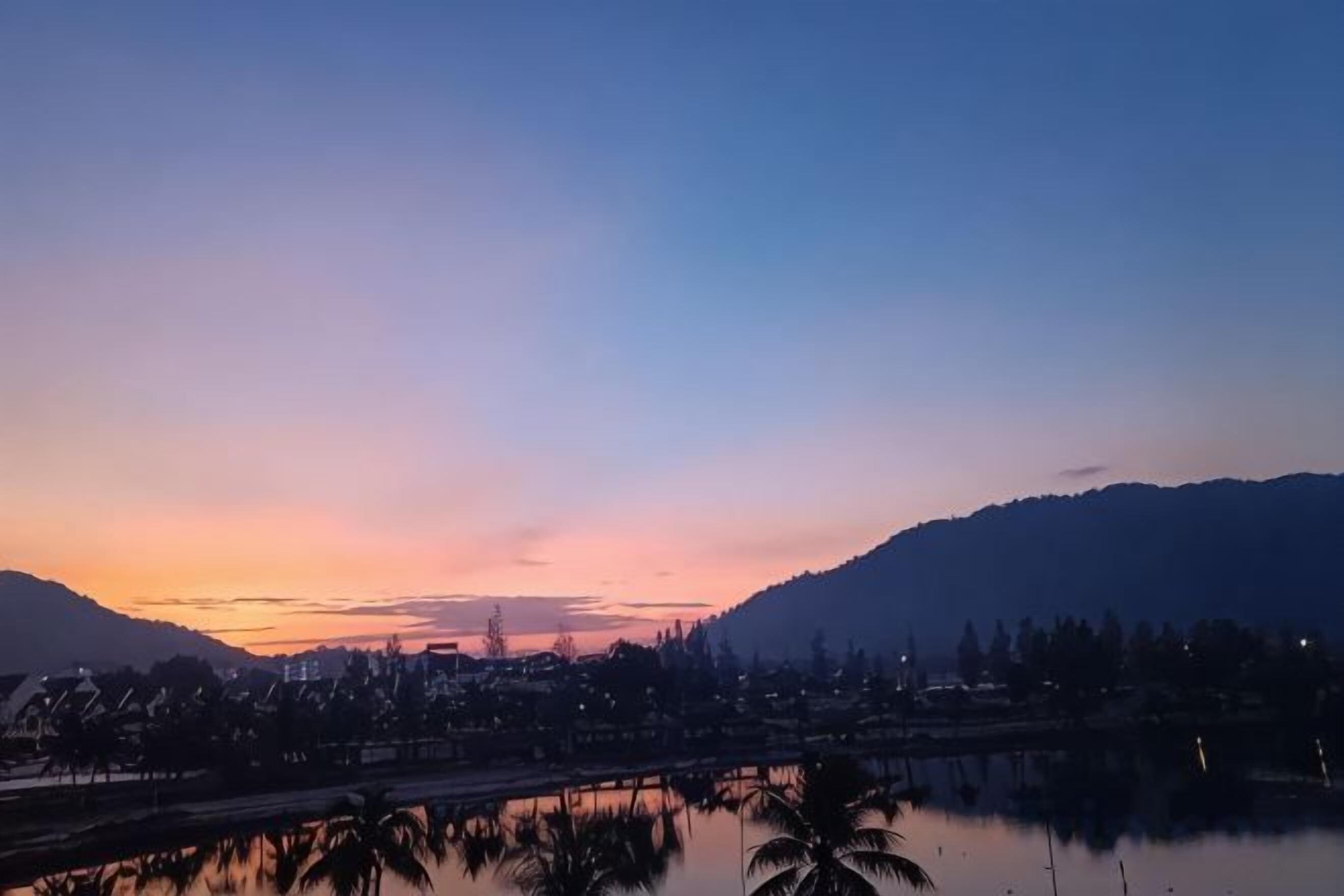 A sunset over a body of water with a bridge and buildings in the background.