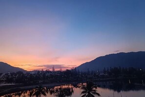 A sunset over a body of water with a bridge and buildings in the background. - Spacious & Homey Apartment at Marina Island by JoMy Homestay (Manjung)