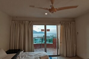 A bedroom with a bed, curtains, a ceiling fan, and a balcony with a view. - Spacious & Homey Apartment at Marina Island by JoMy Homestay (Manjung)