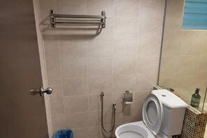 A bathroom with a toilet, a shower, and a towel rack. - Spacious & Homey Apartment at Marina Island by JoMy Homestay (Manjung)