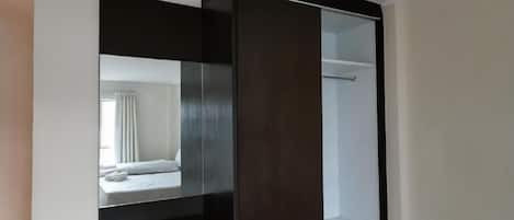 A bedroom with a built-in wardrobe, a mirror, and a bed.