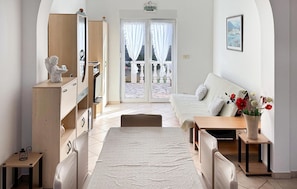 Une pièce confortable avec un lit, un bureau et une chaise. On y trouve également une armoire, une petite table et un vase avec des fleurs.