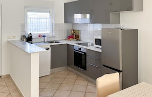 A compact kitchen with a built-in oven, a microwave, and a refrigerator.