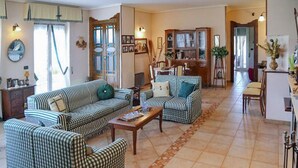 Ein Wohnzimmer mit karierten Sofas, einem Couchtisch und einem Essbereich mit Schrank und Stühlen.