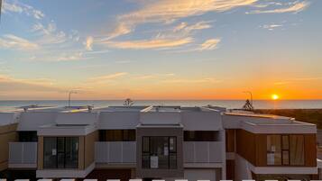 Un edificio moderno con varios balcones con vistas a la puesta de sol sobre el mar.