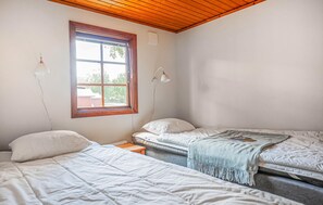 Une chambre avec deux lits, une fenêtre et un plafond avec des poutres en bois.