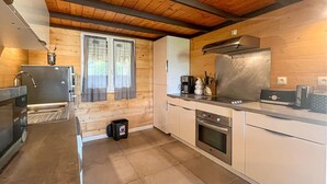 Une cuisine moderne avec des murs en bois, des appareils électroménagers en acier inoxydable et une grande fenêtre agrémentée de rideaux.