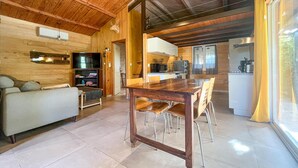 L’intérieur chaleureux d’un chalet en bois comprend une table à manger en bois, des chaises, un canapé et un coin cuisine équipé d’un réfrigérateur et d’un four à micro-ondes.