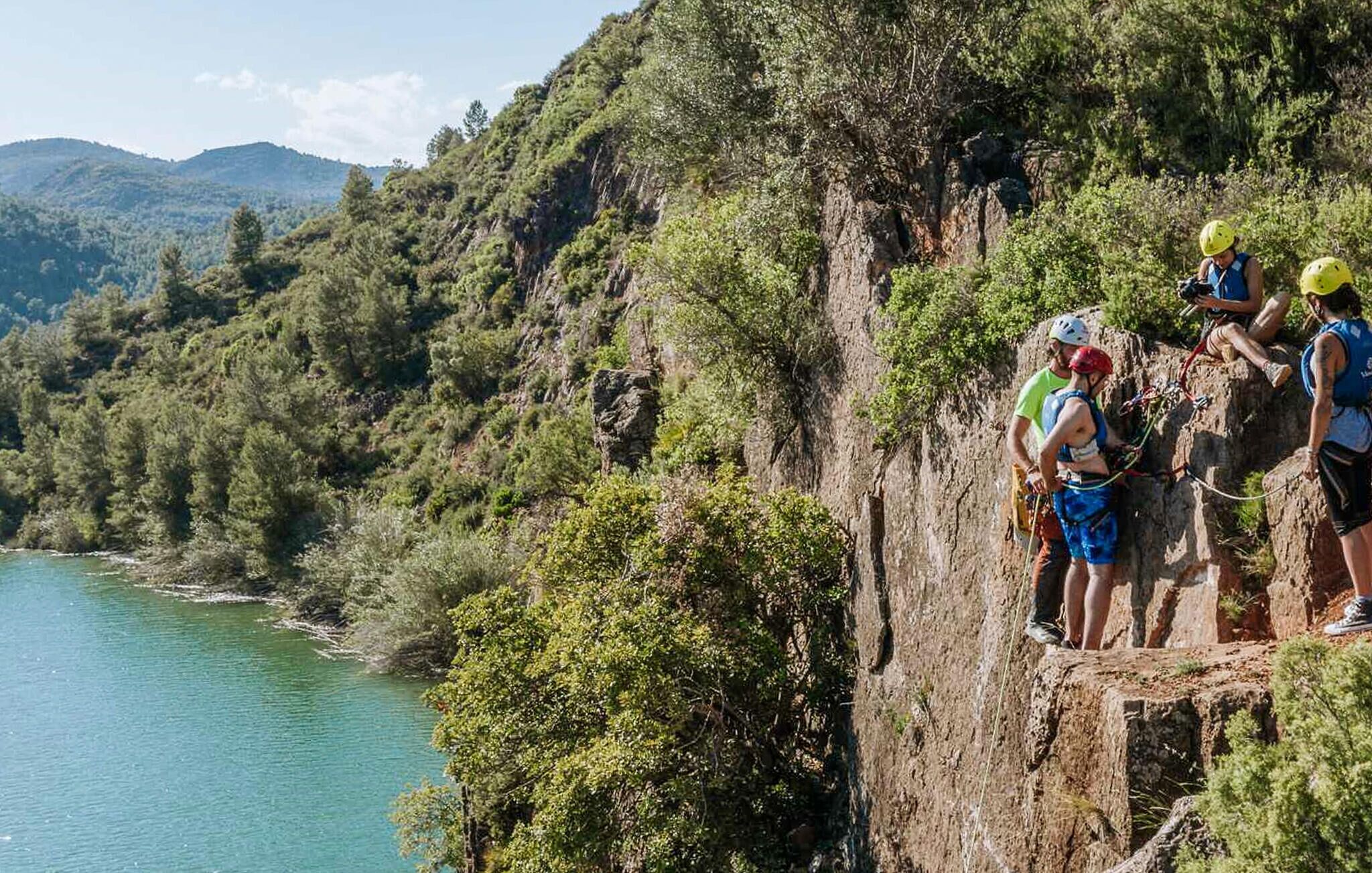 A group of people on a rocky cliff overlooking a body of water.