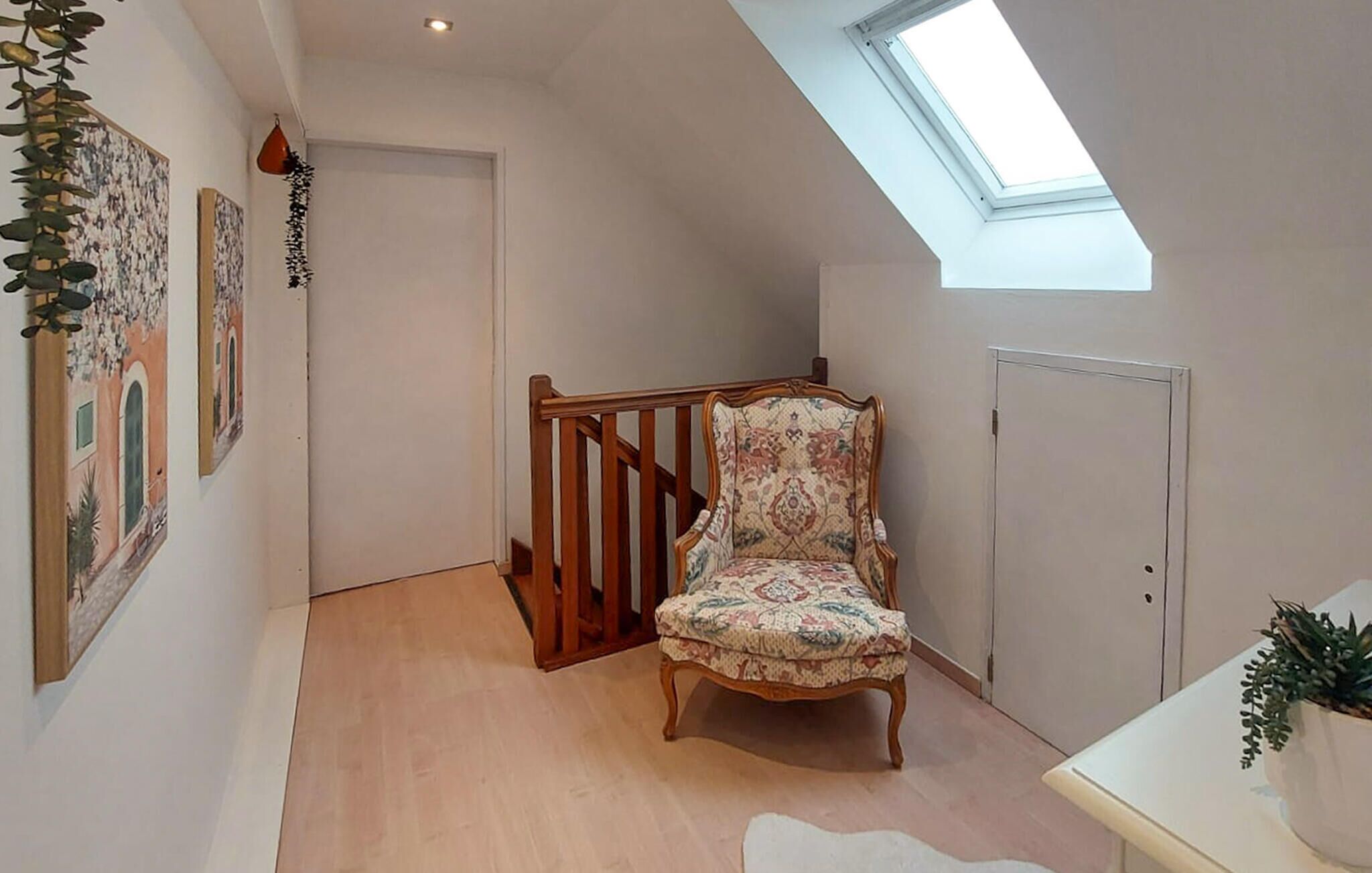Een kamer met een houten stoel, een trap, een dakraam en een deur.
