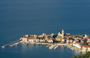 An aerial view of a coastal town with a marina, buildings with red-tiled roofs, and a prominent tower. - Luxurious home in Vinjerac (Vinjerac)