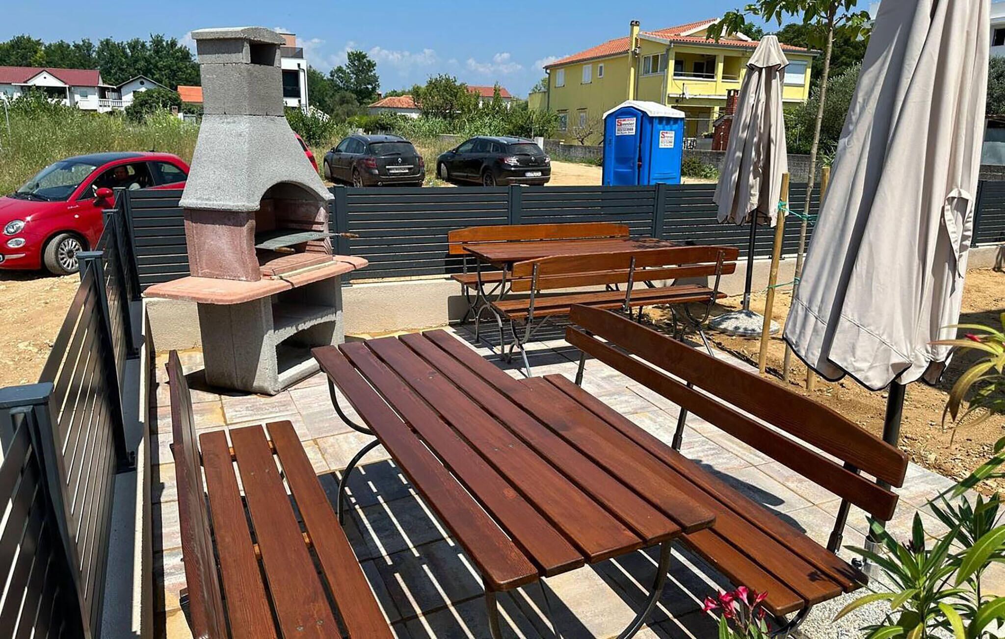 An outdoor seating area with wooden benches and a stone barbecue grill.