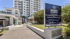 A modern building with a sign for 'Proximity Waterfront Apartments' indicating luxury and holiday accommodations. - Seaside Escape With Pool, Balcony and Views (Redcliffe)