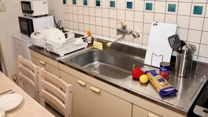 A kitchen with a sink, microwave, toaster, and various food items.