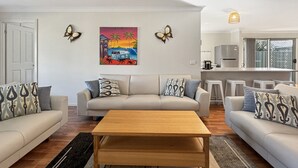 Un salon avec un canapé beige, une table basse en bois et un tableau coloré accroché au mur.