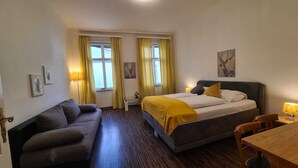 A hotel room with a bed, a sofa, a desk, and a chair. - Cozy 1BR Apt Long Stay for 3 Guests (Vienna)