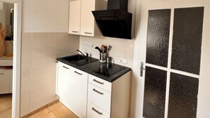 Una cucina moderna con mobili bianchi, un piano di lavoro nero e una lampada a sospensione geometrica.