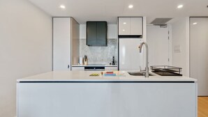 Een moderne keuken met een centraal eiland, witte kasten en een roestvrijstalen spoelbak.