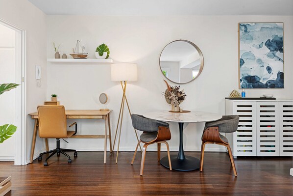 A modern dining area with a round table, two chairs, a lamp, and a decorative mirror. - Contemporary 1-bed Unit Near Chapel St (Melbourne)