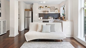 A modern kitchen with white cabinetry, a built-in oven, and a countertop with various appliances. - Contemporary 1-bed Unit Near Chapel St (Melbourne)