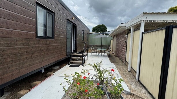 En mobilhome med terrasse, udendørs møbler og krukkeplanter.