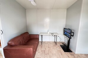Una habitación pequeña con un sofá de cuero marrón, una mesa blanca y un televisor montado en la pared.