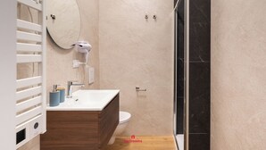 A modern bathroom with a wooden vanity, a large mirror, a toilet, and a shower area. - Barirooms - District 198 (Bari)