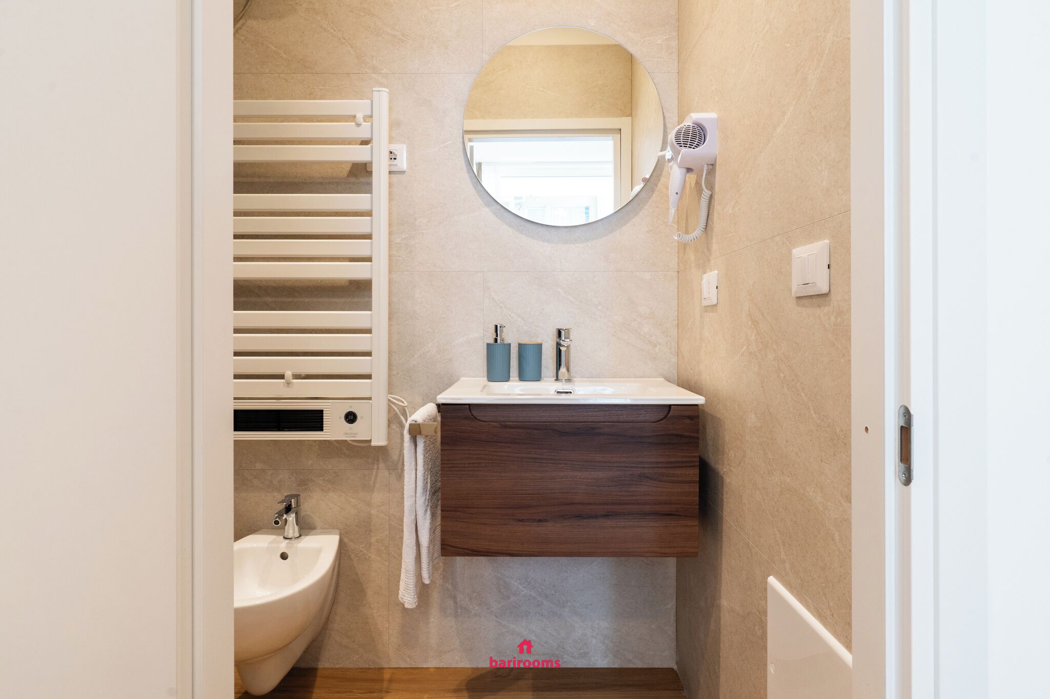 A bathroom with a white sink, a mirror, a towel rack, and a hairdryer.
