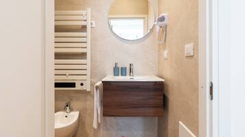 A bathroom with a white sink, a mirror, a towel rack, and a hairdryer.