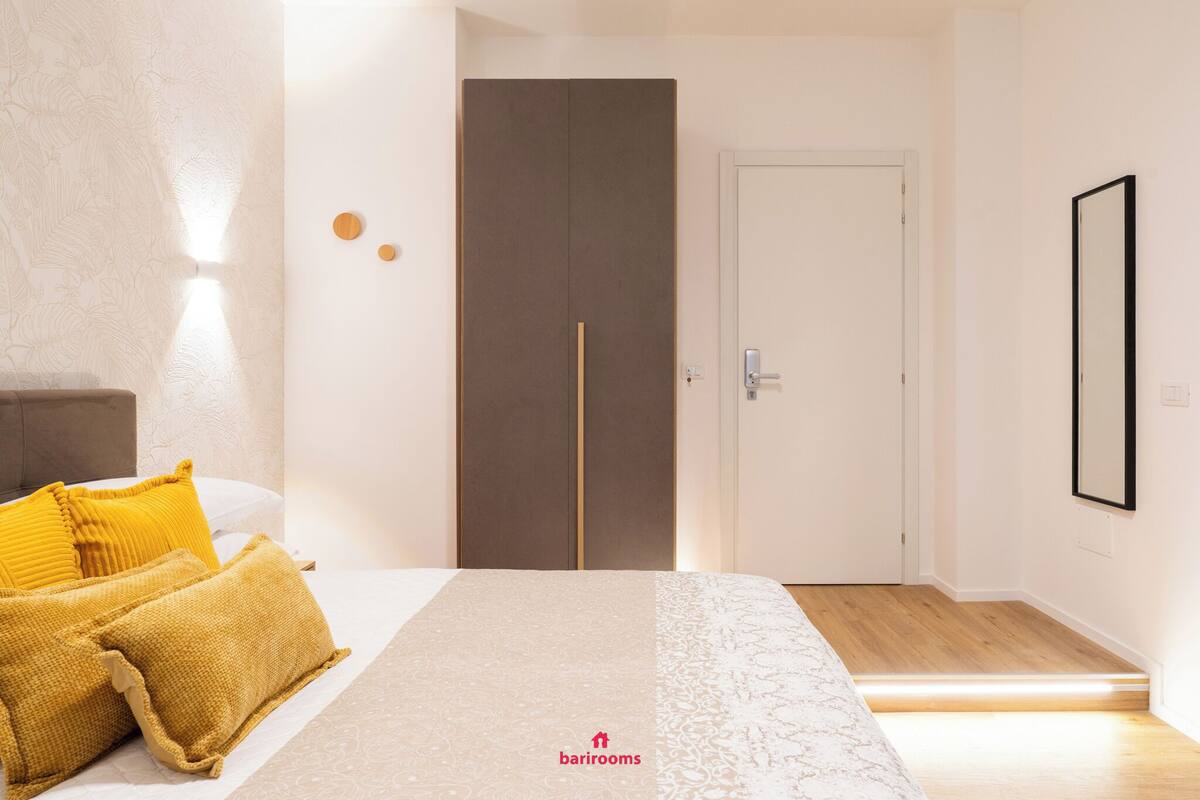 Une chambre à coucher avec un lit, deux oreillers, une armoire, une porte et un miroir.