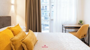 A hotel room with a bed, a desk, and a chair. - Barirooms - District 198 (Bari)
