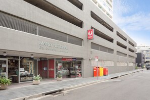 Un edificio con un letrero que dice 'Manly National', una tienda 'POST' y una zapatería 'Manly Cobbler's'.