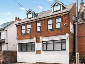 Un edificio de ladrillo de dos pisos con un letrero que dice Hilltop Serviced Apartments en el número 122 de la calle High - Earl Shilton.