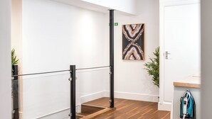 Ein modernes Interieur mit Holzboden, Glastrennwand und einem an der Wand befestigten Kunstwerk.