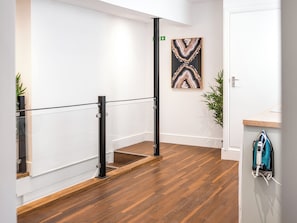 A modern interior with a wooden floor, a glass railing, and a wall-mounted artwork.