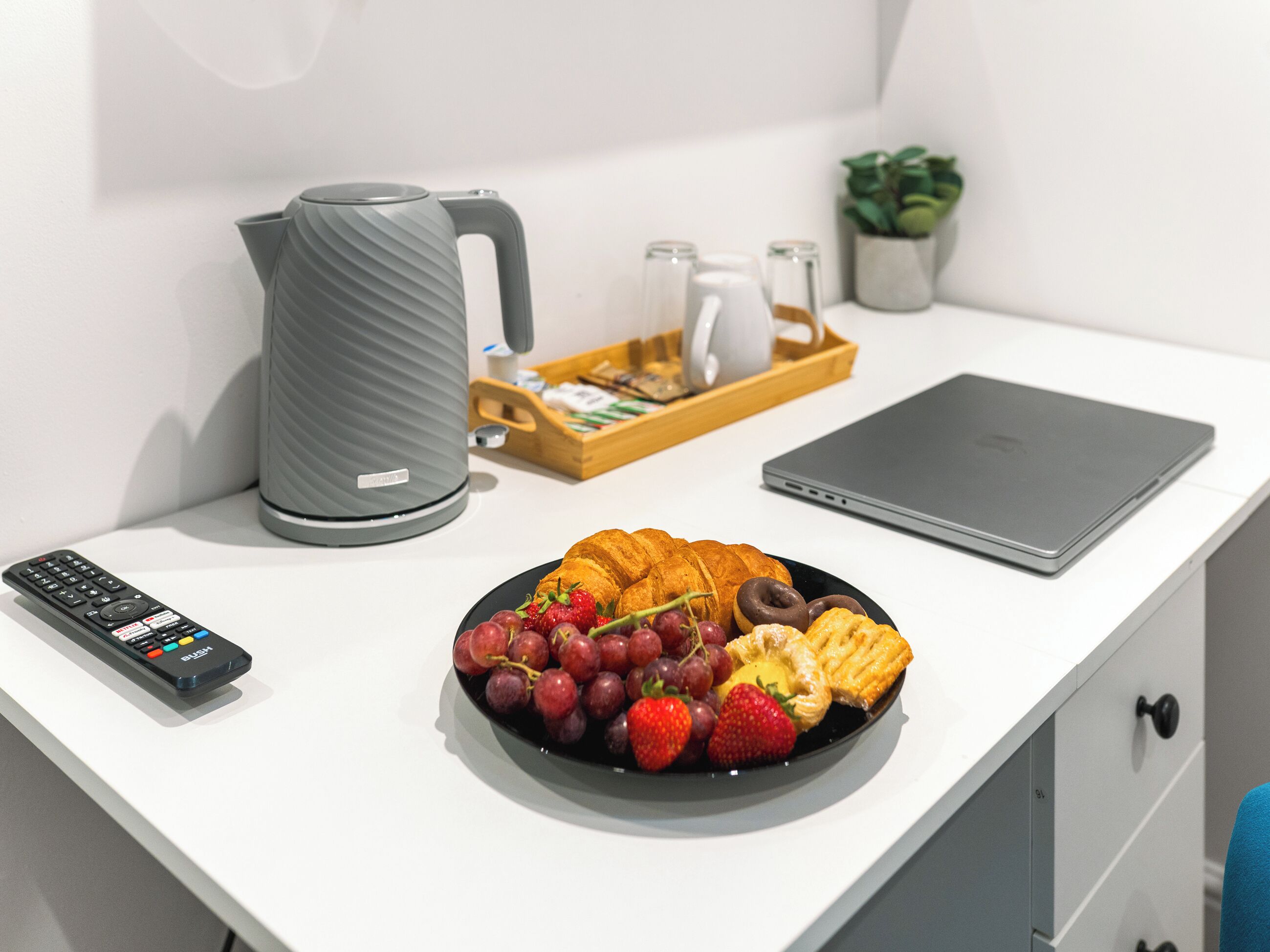 A breakfast tray with croissants, strawberries, and chocolate on a white table.