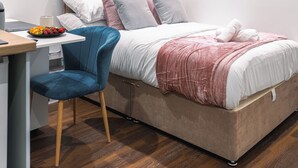 Ein ordentlich eingerichtetes Schlafzimmer mit einem Bett, einem Schreibtisch und einem Stuhl.