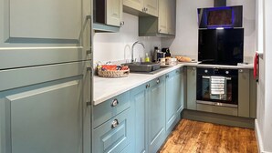 A modern kitchen with light blue cabinets, a built-in oven, and a microwave. - 2 bedroom accommodation in Hexham (Hexham)