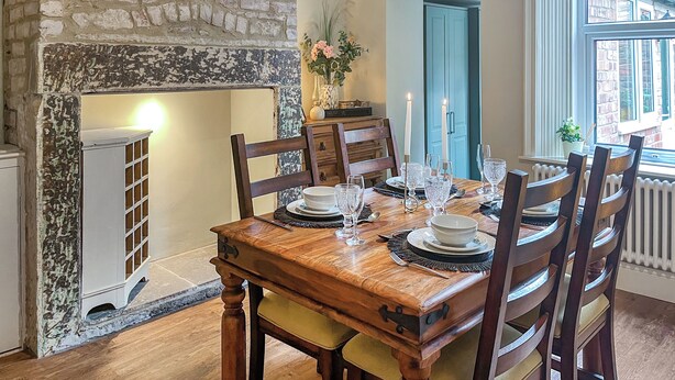 A dining room with a brick fireplace, wooden table, and chairs. - 2 bedroom accommodation in Hexham (Hexham)