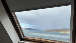 Une fenêtre de toit offrant une vue sur un paysage côtier.