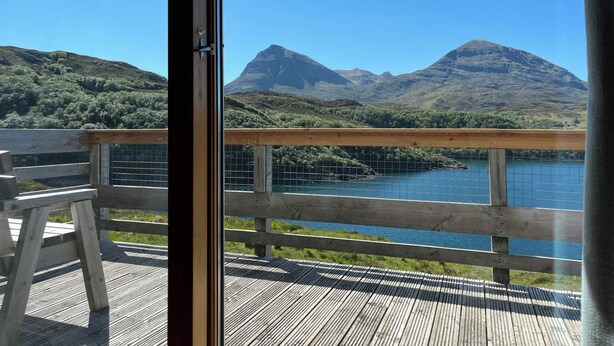 Une terrasse en bois offrant une vue sur un lac et des montagnes.
