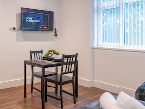 Ein Essbereich mit Tisch, Stühlen, einem Bonsai-Baum und einem Fernseher, der eine Netflix-Werbung zeigt.